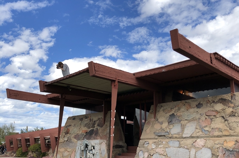 Woman on the roof of stone and wood building with camera in hand