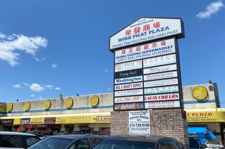 sign with vietnamese in front of strip mall with parking lot