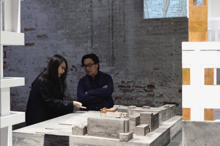 Two people standing behind concrete model