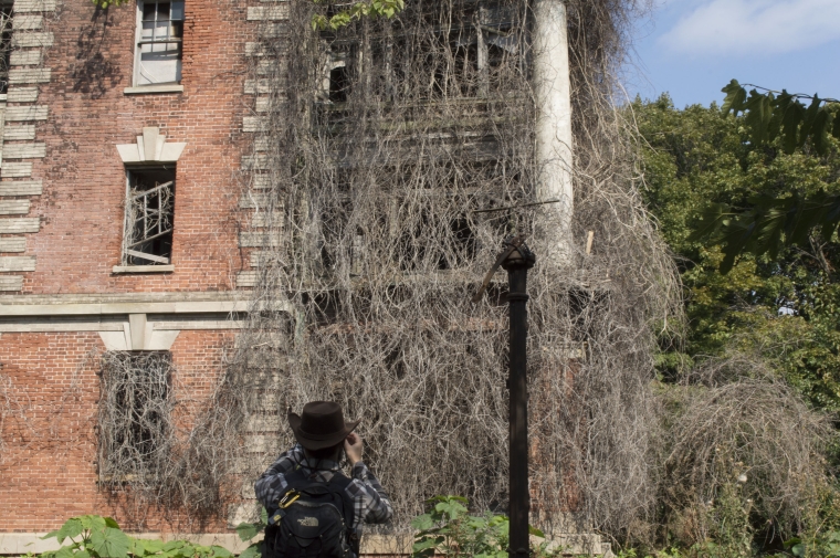 Student Evan Oskierko-Jeznacki takes a picture of the overgrown Nurse's Home. Photo by Andrea Haley.