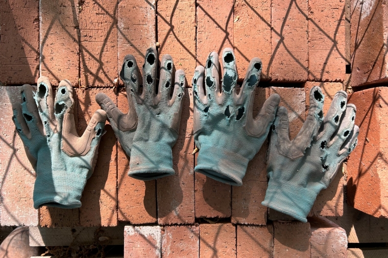 worn work gloves lay on red bricks