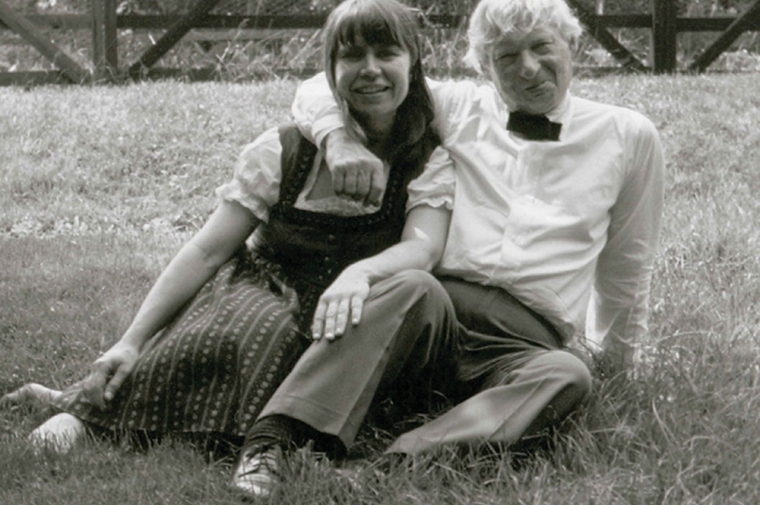 A young woman and middle-aged man sitting close together on the grass