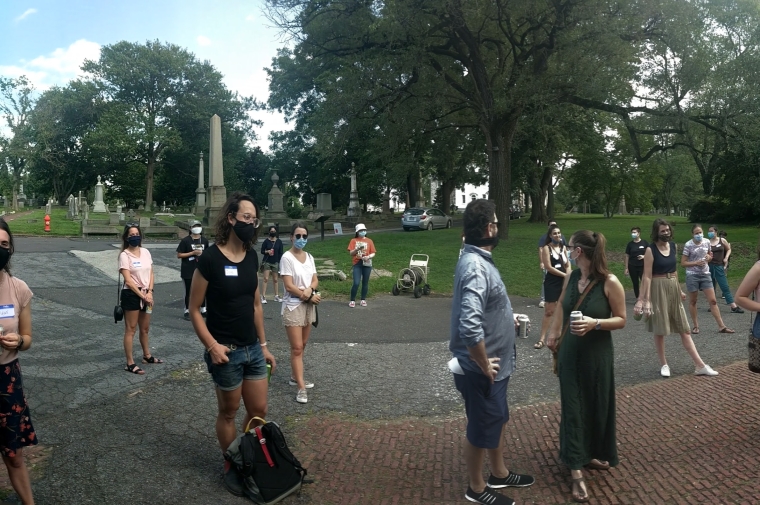 panoramic photograph of students, masked, in a cemetery. 