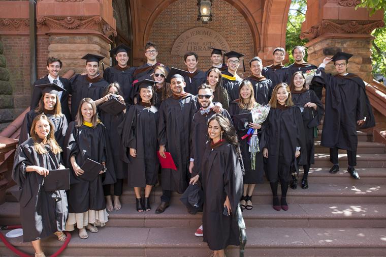 Photograph of Weitzman school graduates in regalia on the steps of the Fisher Fine Arts Library