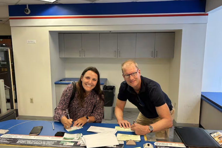 Two people posed signing a letter 