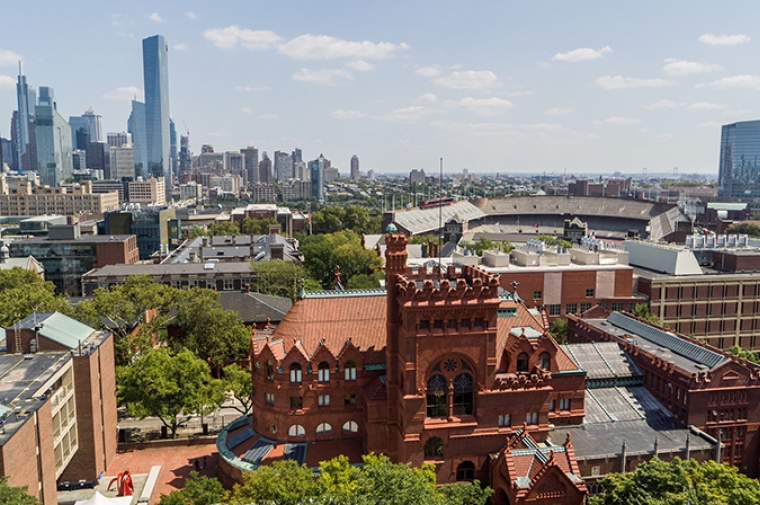 Ornate red brick building next to brutalist building with Philly skyline in distance