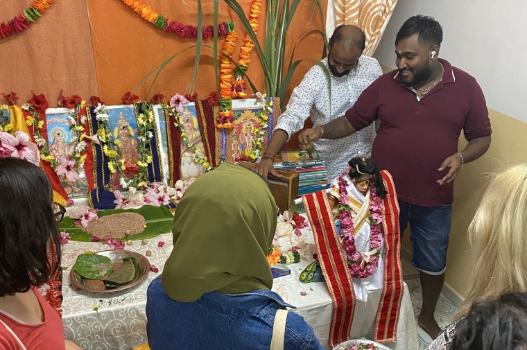 A man points to an elaborate alter on a table while people look on