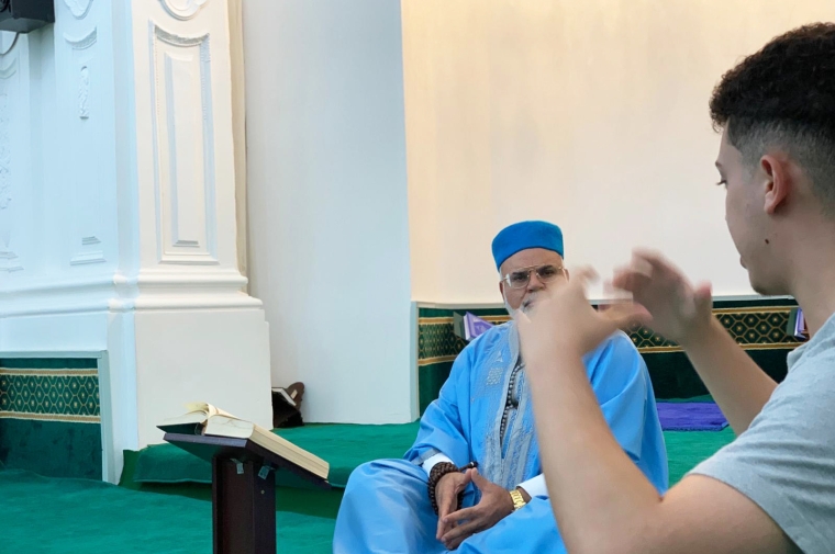 Two people talk while sitting on the ground