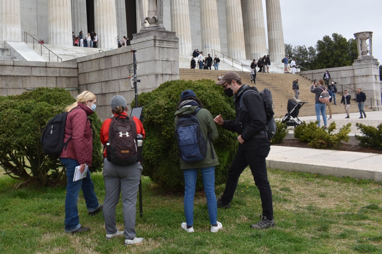 Group of people with survey equipment in front of white NeoClassical facade