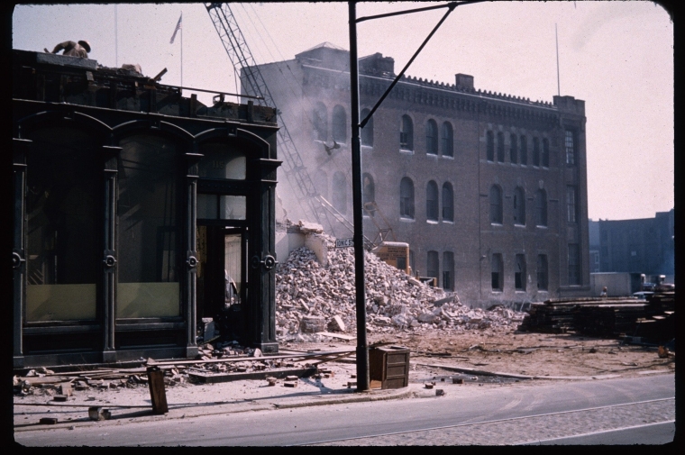 Building rubble piled up on a vacant city lot between two historic buildings