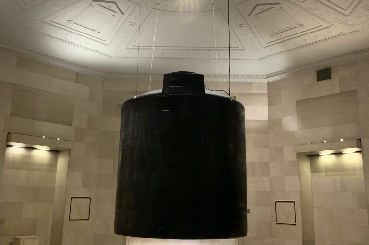 image of artwork installation. large object suspended from ceiling, looking up