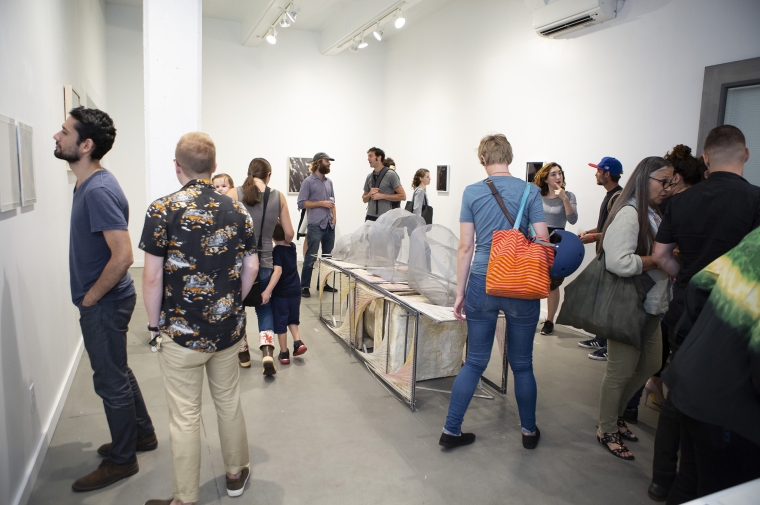 A crowd browses artwork on the walls in a white gallery