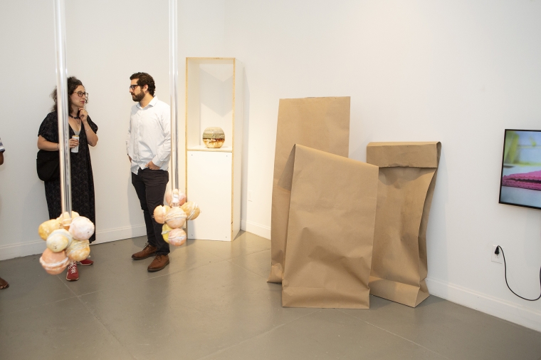 Two men chatting next to brown paper floor sculptures