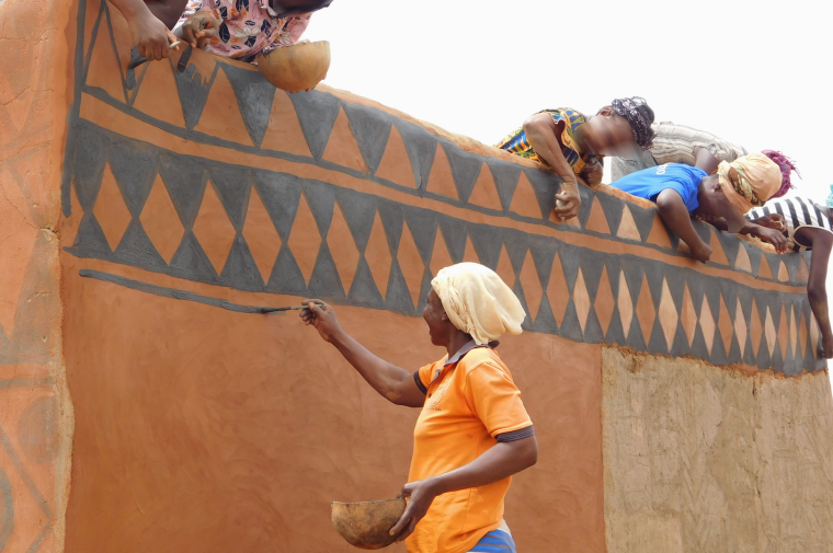 African women adorn mud walls with black decorative paint. (Copyright Amélie Esséssé)