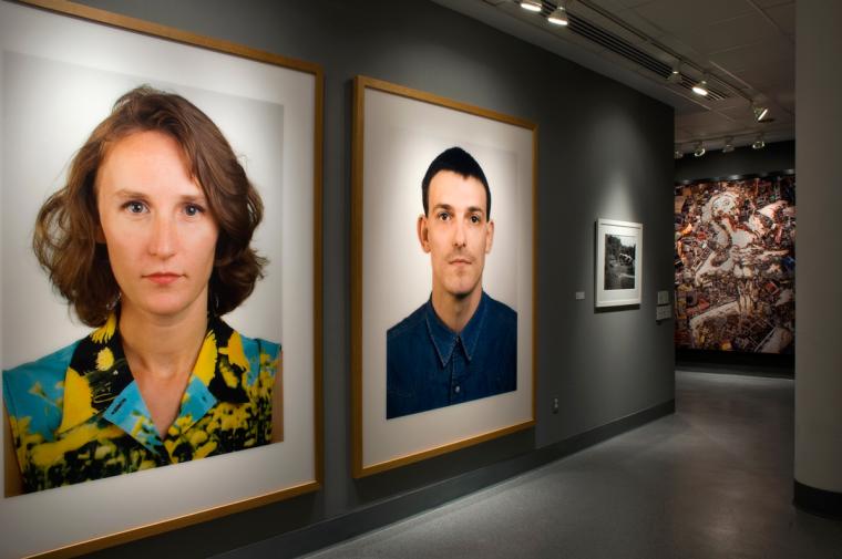 Gallery display of photographs. Most notable pieces are large portraits of a woman and a man.