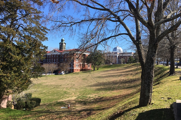 Grassy hills and two stately brick buildings