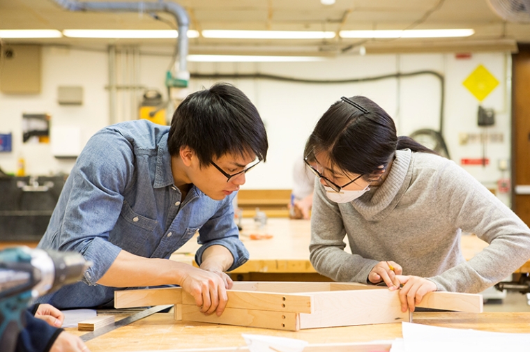 Two students working together on a wooden frame a studio