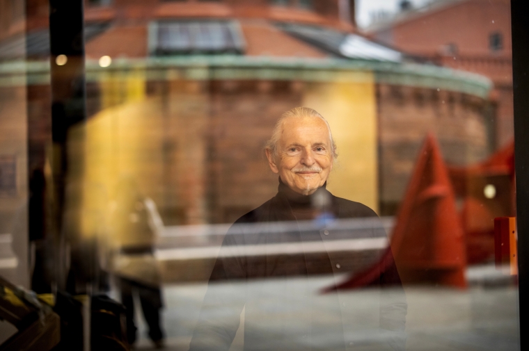 Krzysztof Wodiczko seen through a glass window