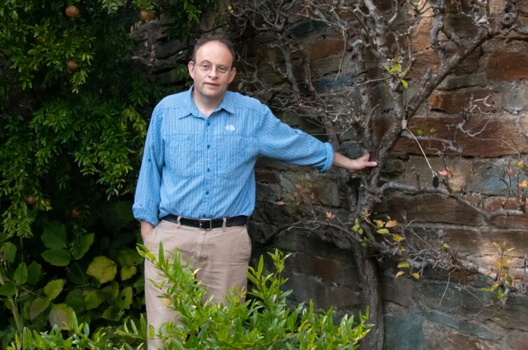 Wunsch standing by bush and tree in blue shirt