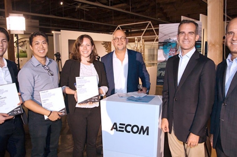 A group of six people pose next to a pedestal with the word AECOM on it