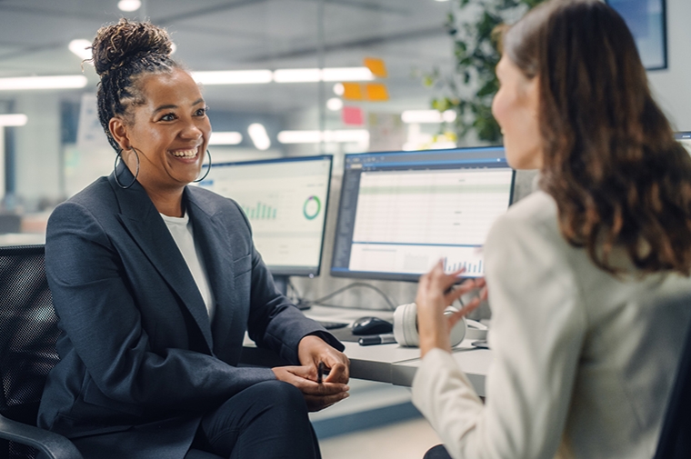 Two women in a professional setting (office) talking in an interview.