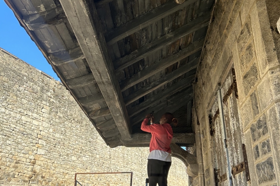 student surveys underside of a wooden eave