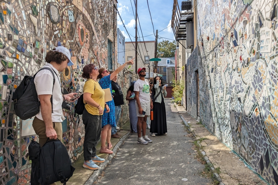 studio group stands in mosaicked alley