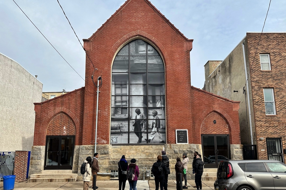 People standing in front of an old church with an installation in windows