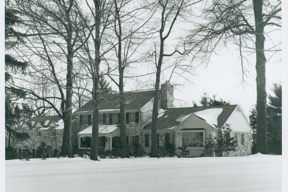 black and white photo of colonial revival house in the snow