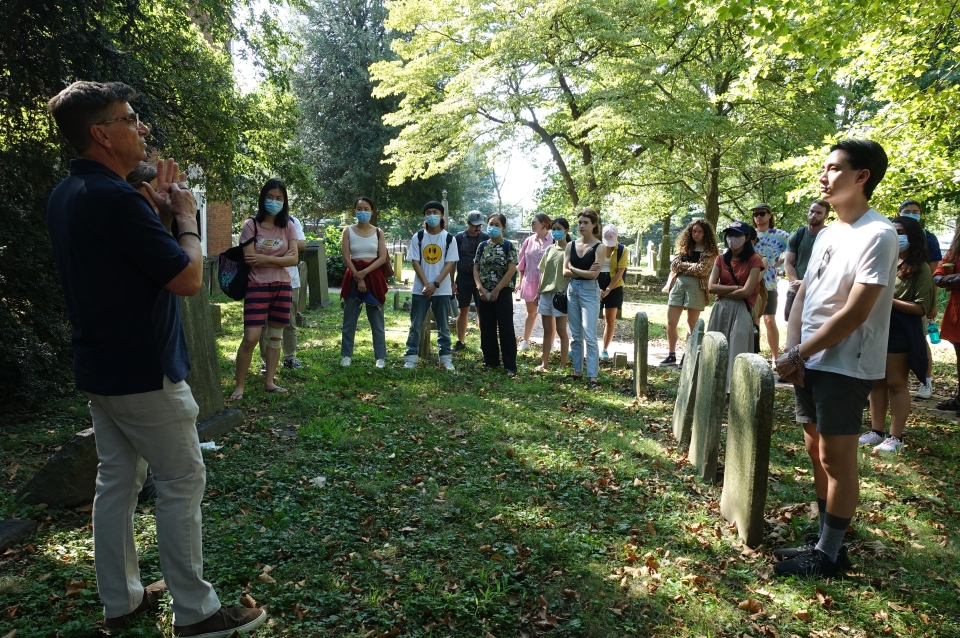 Students gather for lecture in lush green cemetery