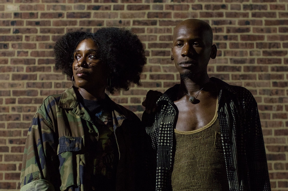 Portrait of the artists in front of a brick wall