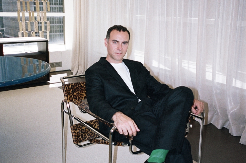 Photo portrait of Jonathan Olivares reclining in a chair in a high-rise building