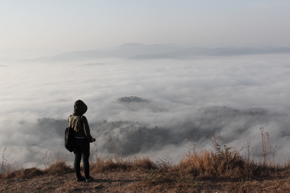 Student on mountain overlooking clouds below
