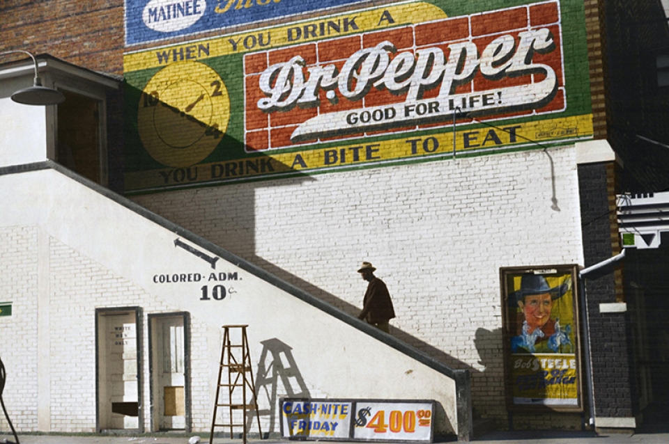 A man with a hat walks up an exterior staircase