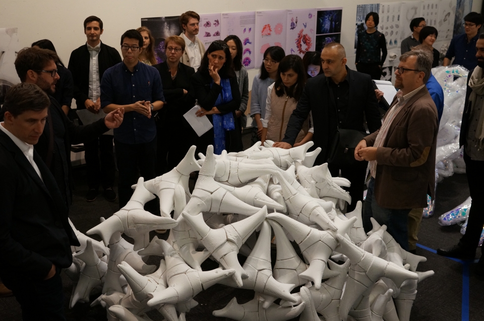 Group gathered around a sculpture that resembles a pile of bones