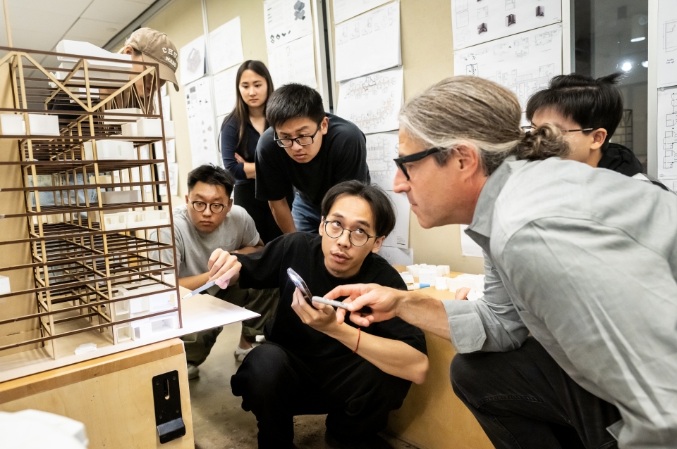 Students crouched around wooden architecture model