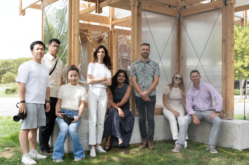 Group of people standing outdoors next to wood pavilion