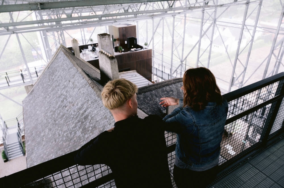 Two people look down on house from a platform at the top of the shelter overtop                          