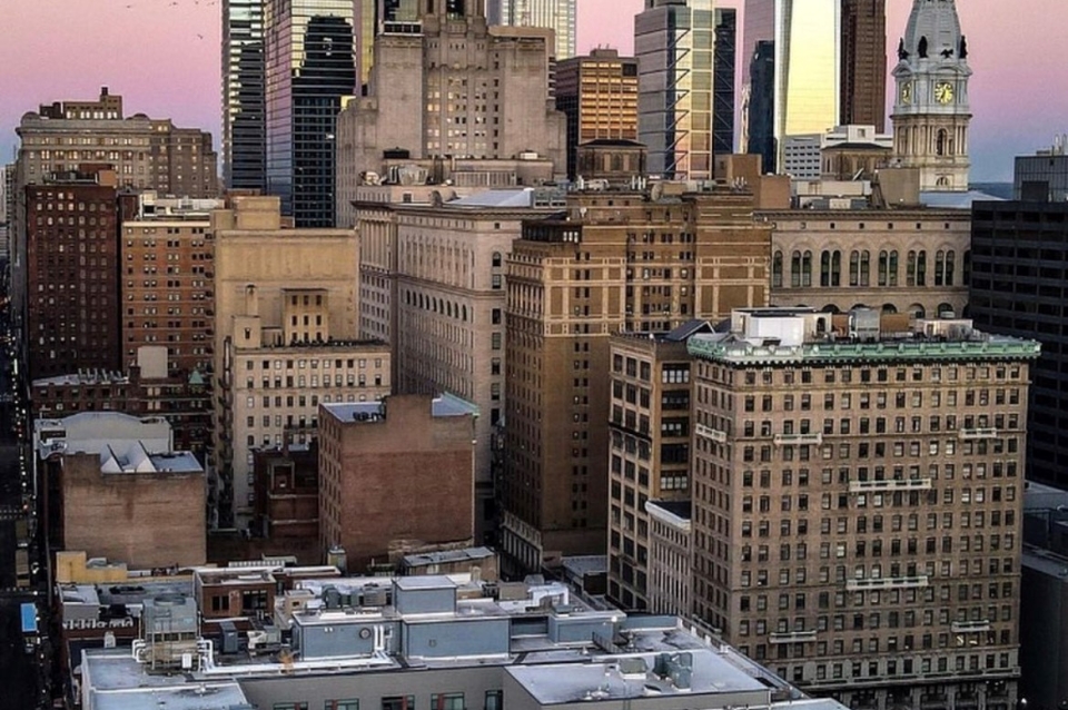 Philadelphia skyline during sunset featuring a mural which includes an image of a Philadelphia teenager