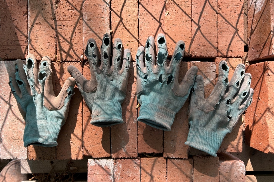 worn work gloves lay on red bricks