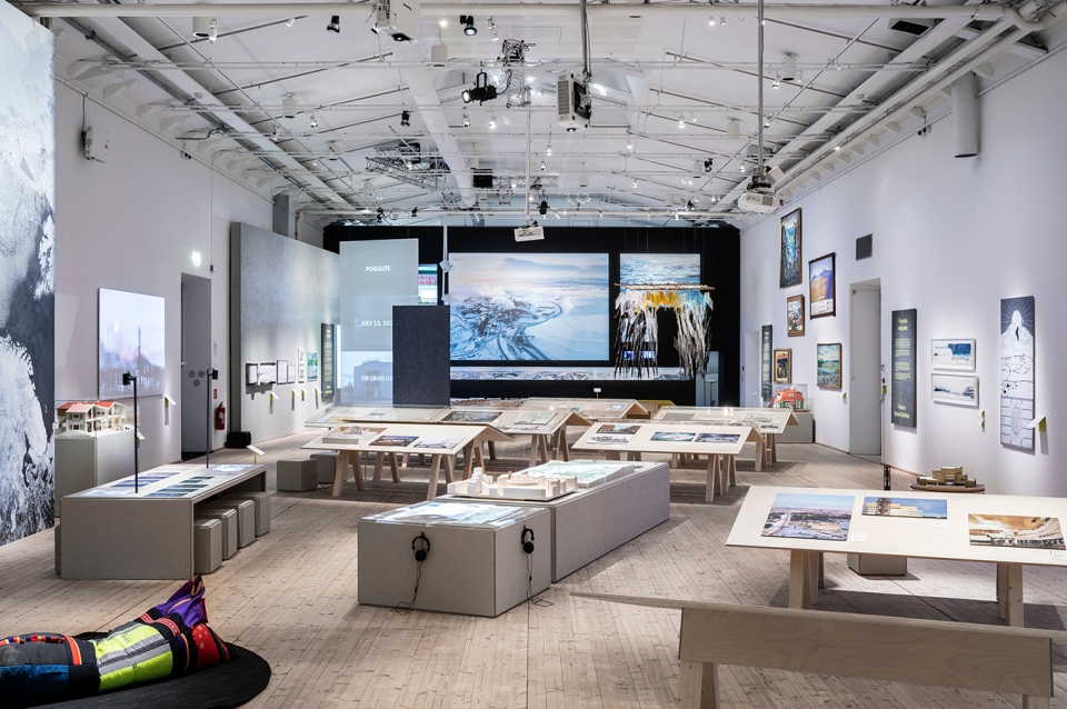 Large gallery space with many images displayed. There is a sitting area where one can sit and view images closely