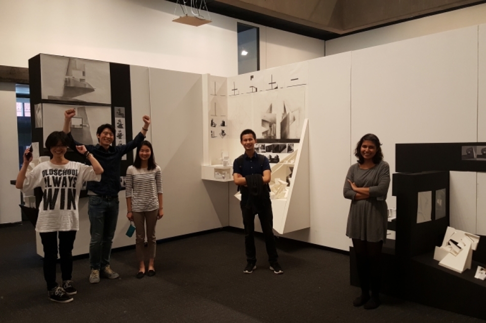 Students standing beside their pieces in gallery display