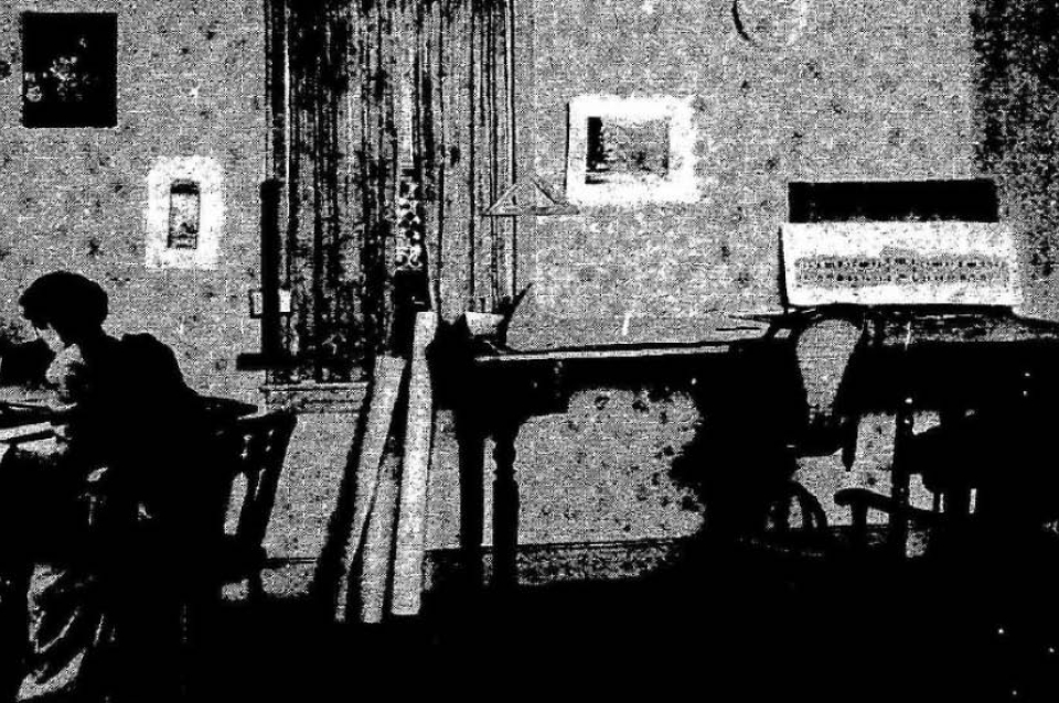Black and white photo of a woman's silhouette at a drafting table
