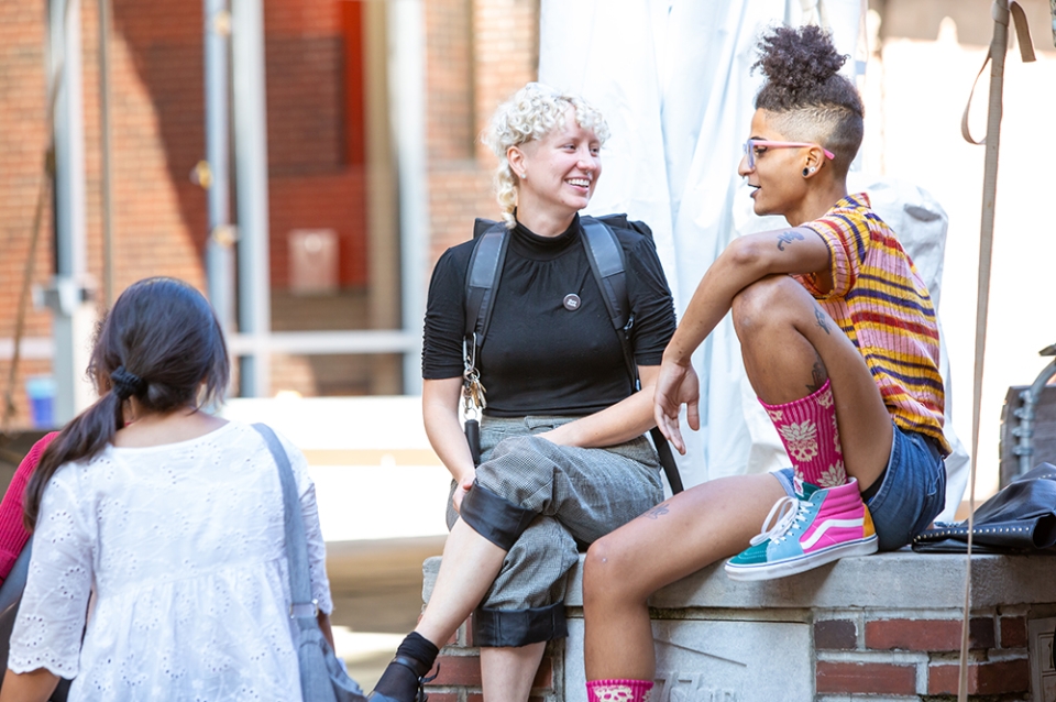 Two students chatting on the bench in front of Meyerson Hall