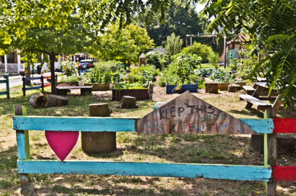 Sign saying "keep this park beautiful" with vegetable garden behind it