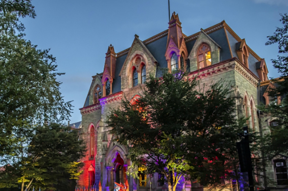 College Hall in the evening time with colored spotlights giving it a dramatic look