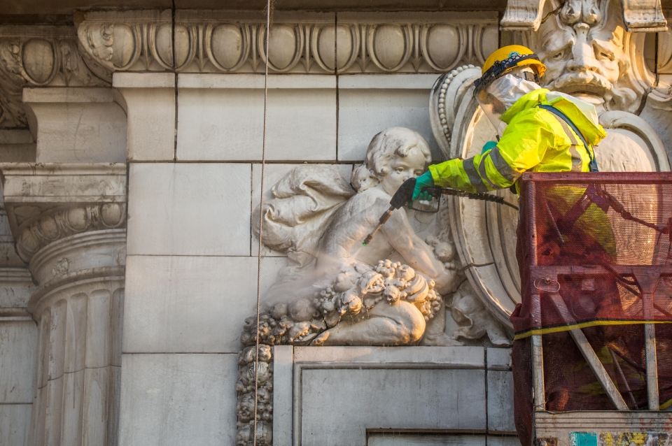 Man restoring detail on stone carving on building