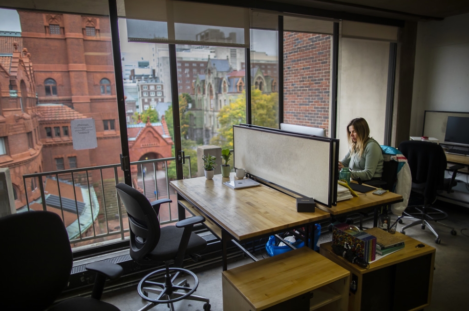 Student working at studio desk next to a large window looking out at Fisher Fine Arts building.