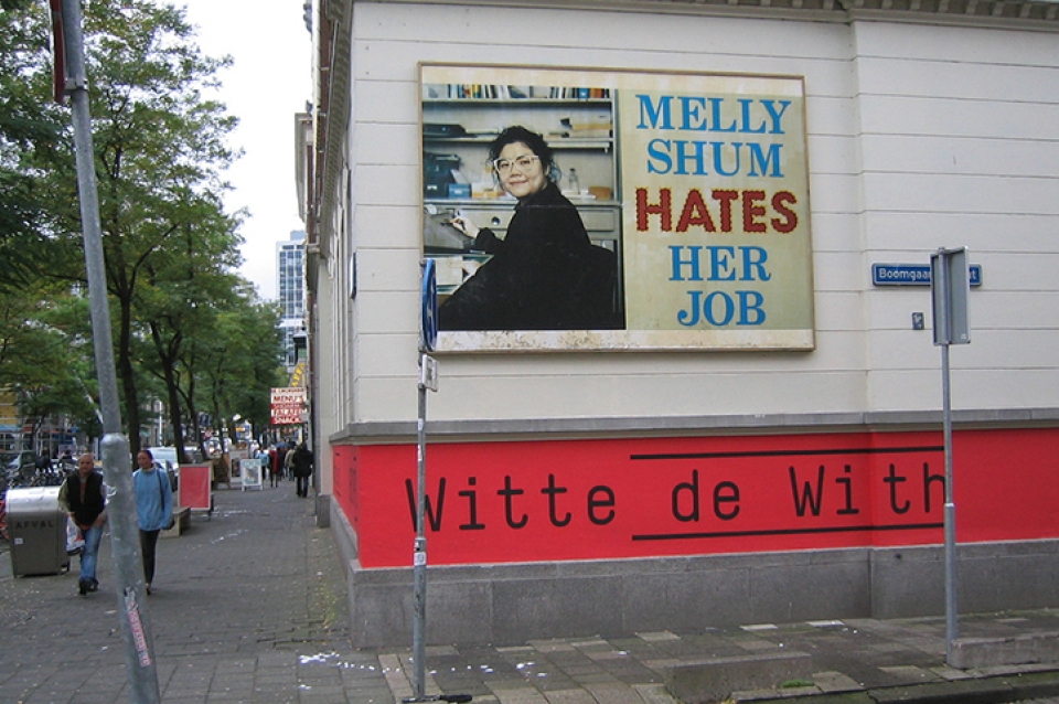 The exterior installation of a work by Ken Lum on a white wall along a street 
