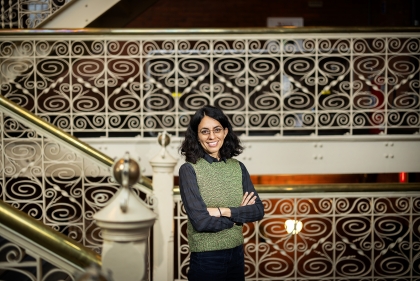 Lopez posing in front of a complex white metal staircase